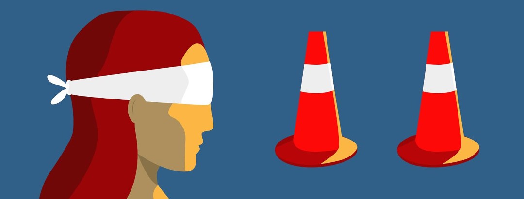 Blindfolded woman looking at traffic cones.