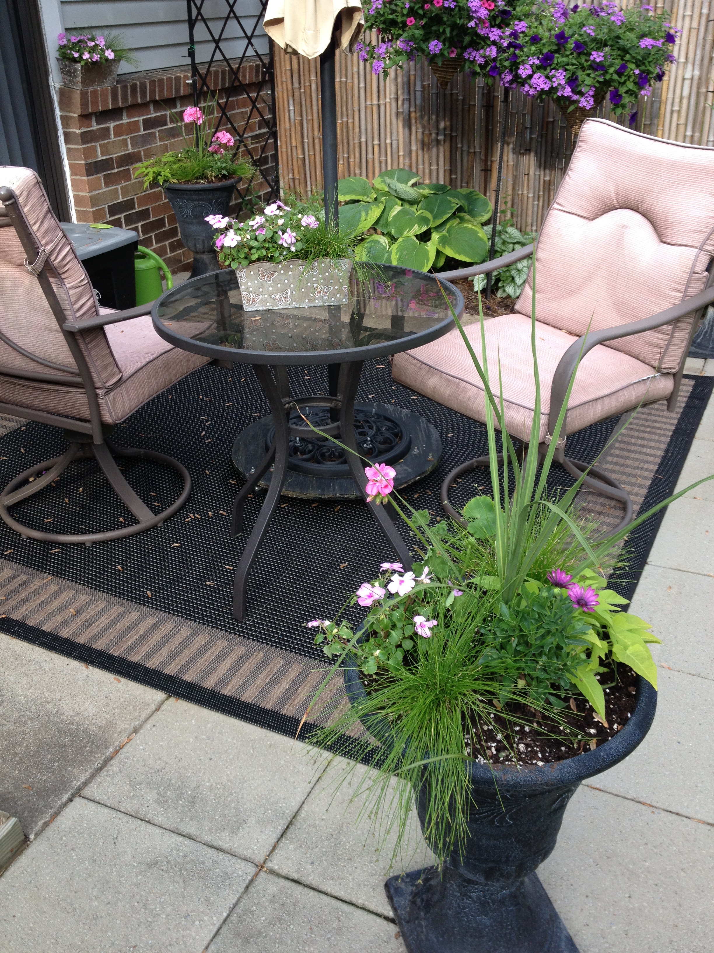 Patio with a table and two chairs near potted plants. 