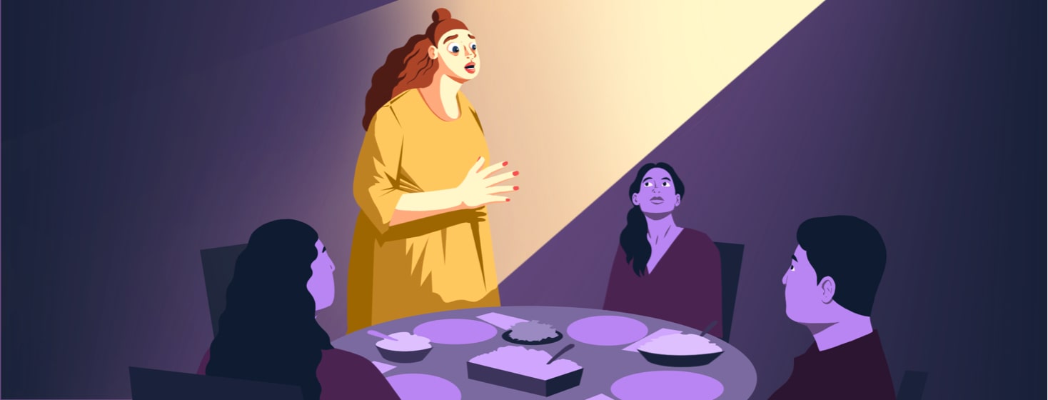 A woman stands in the spotlight and talks to others at the same dinner table